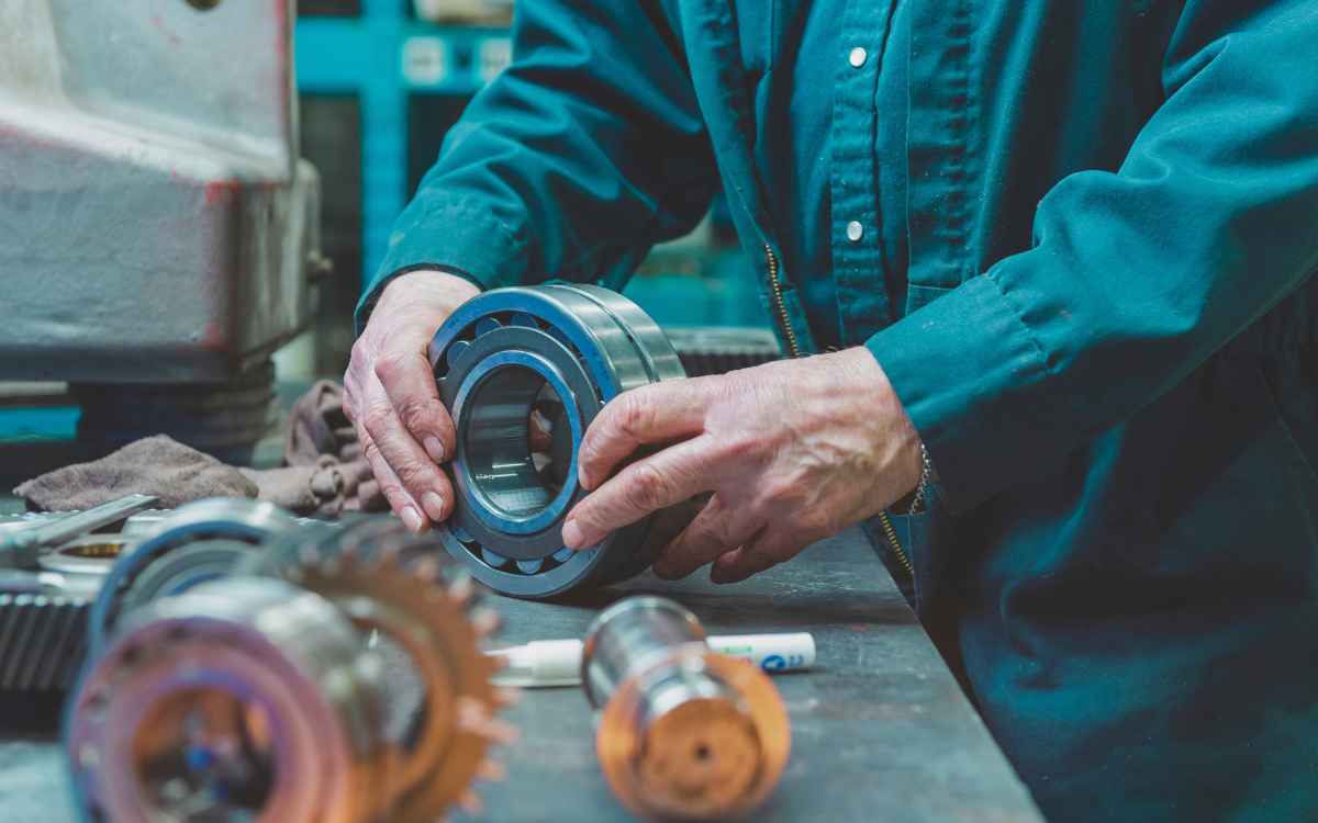 Vemos una imagen de una persona trabajando una pieza de metal, en referencia a la reducción de tiempos en las fábricas con la metodología SMED.