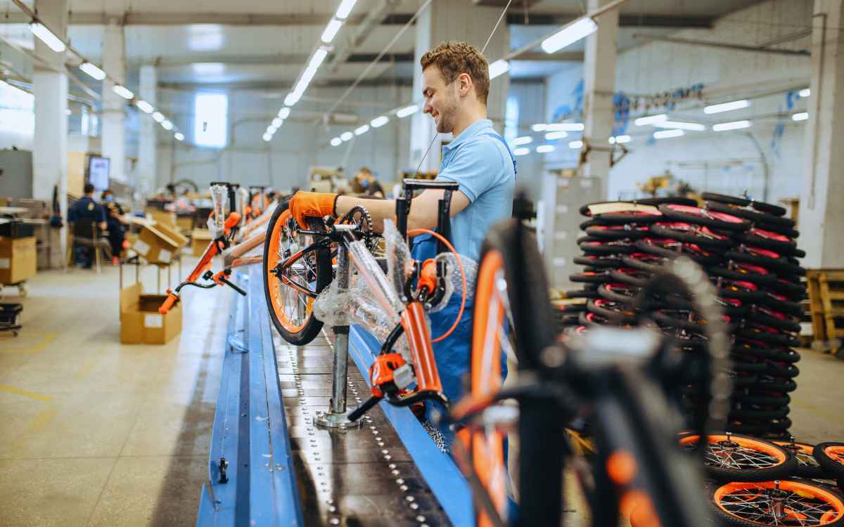 Vemos un obrero armando una bicicleta en una fábrica, en relación con el ejemplo brindado para ilustrar un plan agregado de la producción.